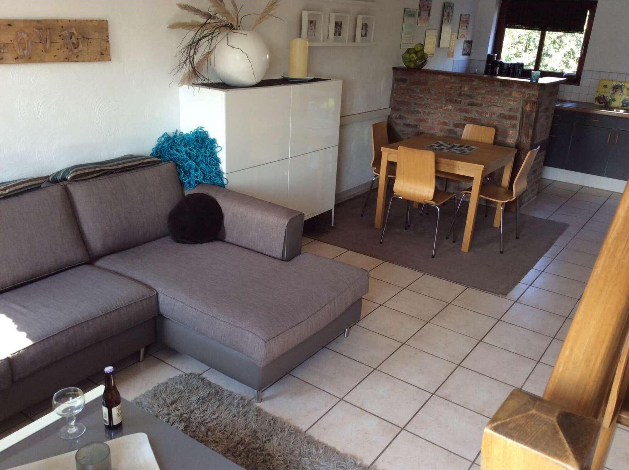 A modern living room with a grey sectional sofa, a small coffee table, and a dining area with a wooden table and chairs.