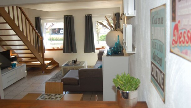 Een woonkamer met een trap, een bank, een salontafel en een potplante.