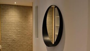 Un couloir avec un grand miroir rond au mur, un mur en bois à texture et un plancher en bois.