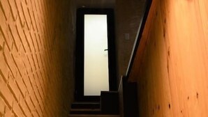 Un escalier en bois, avec un mur de briques d’un côté et un panneau en bois de l’autre, mène à une porte située en haut.