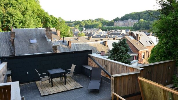 Une terrasse sur le toit, aménagée avec du mobilier d’extérieur, offrant une vue sur le paysage urbain et dotée d’une plateforme en bois.