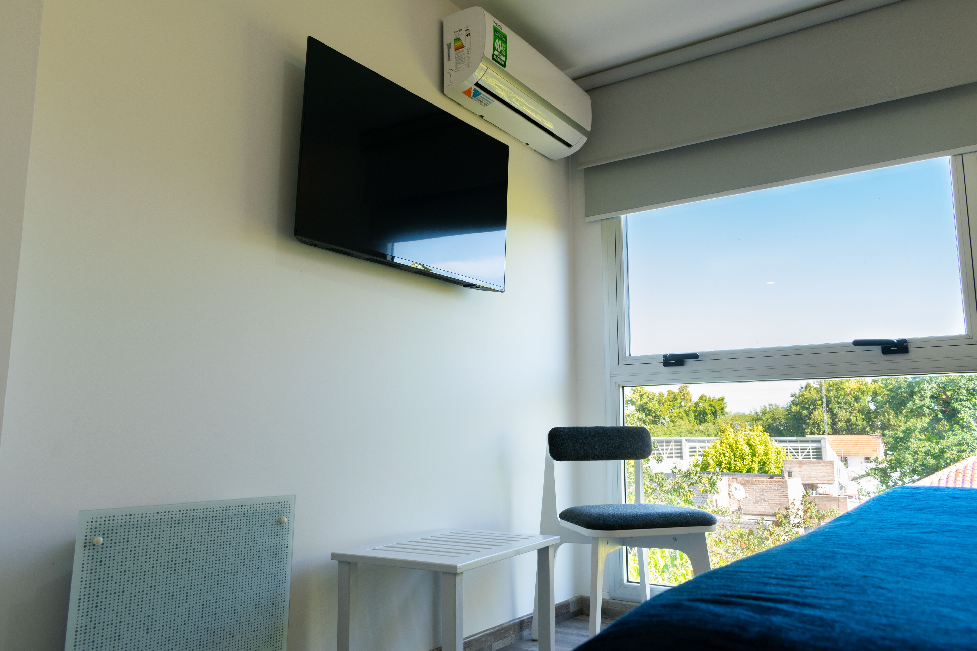 A room with a bed, a TV mounted on the wall, a window, and a chair.