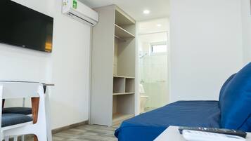 A hotel room with a bed, a TV mounted on the wall, a chair, and a bathroom visible through an open door.