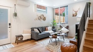 A modern living room with a grey sofa, a coffee table, and a staircase.