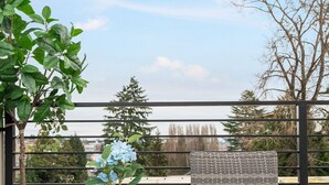 A balcony with wicker furniture, a striped rug, and a potted plant.