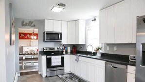 Een moderne keuken met witte kasten, roestvrijstalen apparatuur en een zwart aanrecht.