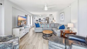 A modern living room with a sofa, coffee table, and TV. - Sandy Bits Oceanfront Premium Condo with Pool (North Myrtle Beach)