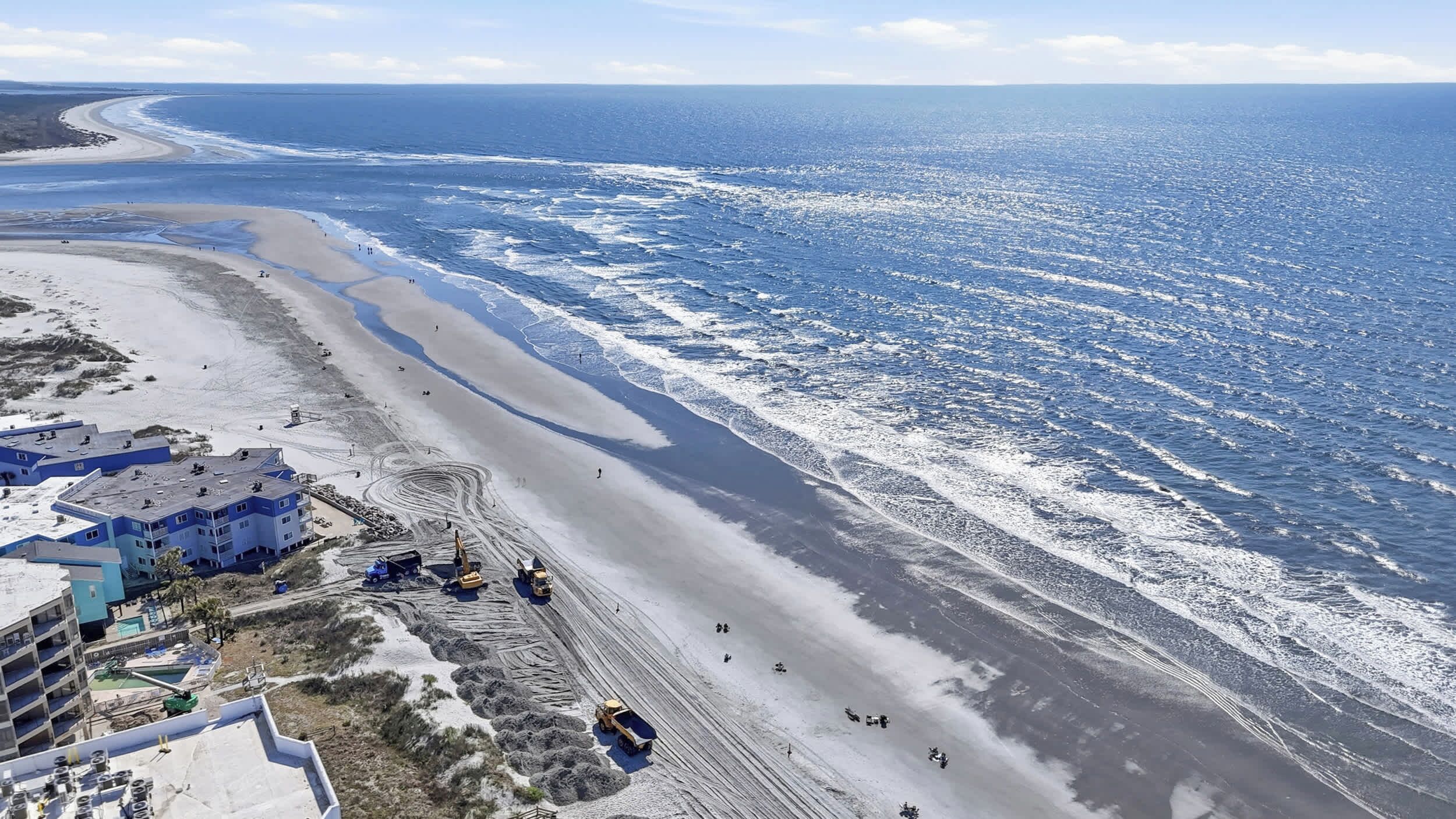 A coastal hotel with multiple floors, a sandy beach, and ocean views.