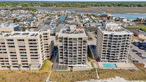 A high-rise hotel with multiple balconies, a swimming pool, and a view of the surrounding residential area. - Sandy Bits Oceanfront Premium Condo with Pool (North Myrtle Beach)
