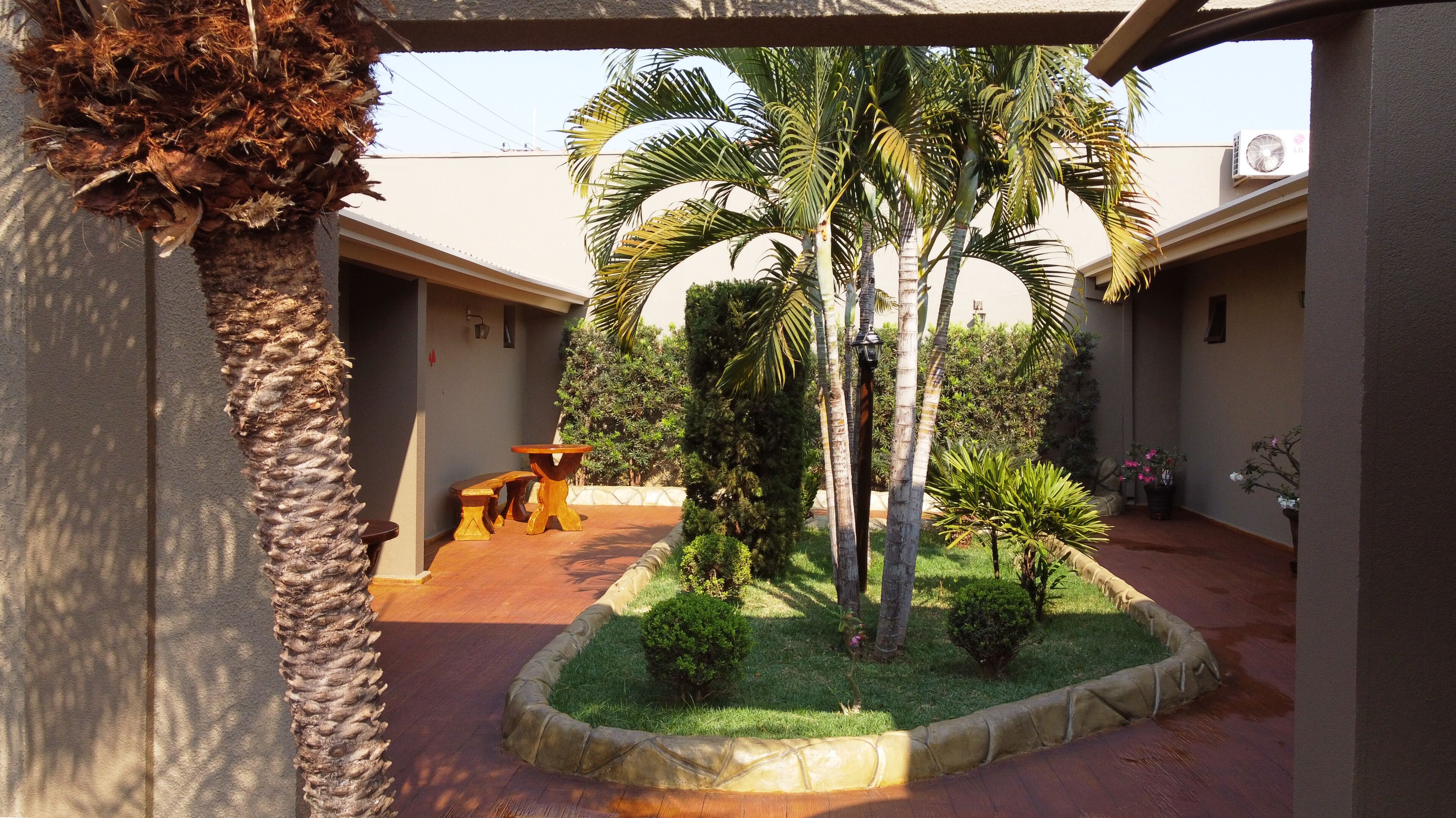 Un patio con palmeras, un banco de madera y un pequeño jardín.