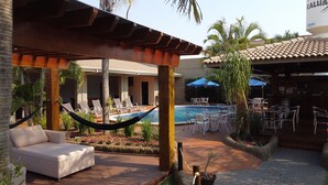 Zona de piscina con sillones de descanso, una hamaca y una piscina pequeña.