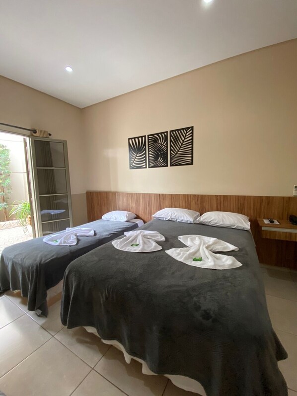 Habitación de hotel con dos camas, cabecera de madera y puerta corredera que da a un balcón.