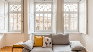 A modern living room with a grey sofa, a small table, and a yellow pillow. - São Bento Deluxe 42 (Porto)