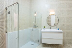 A modern bathroom with a glass-enclosed shower, a white sink with a mirror, and tiled walls. - São Bento Deluxe 42 (Porto)