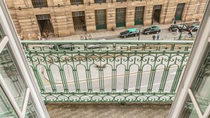 A view from a window overlooking a building with arched windows and a green metal railing. - São Bento Deluxe 42 (Porto)