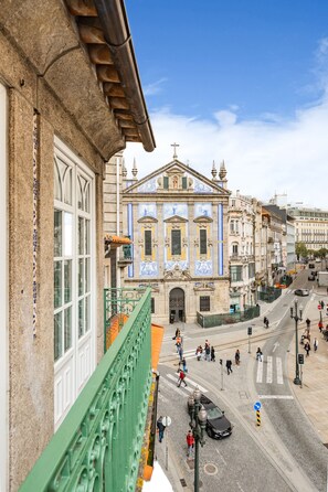 A street view with a building featuring ornate architecture and a cross on top, indicating a religious building. - São Bento Deluxe 42 (Porto)
