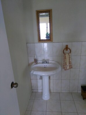 Une salle de bain avec un lavabo blanc, un miroir et un porte-serviette.