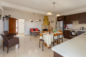 Una cuina àmplia amb electrodomèstics moderns, una zona de menjador amb taula rodona i una zona d'estar acollidora amb sofà.