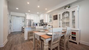 A spacious kitchen with white cabinetry, a central island, and a dining area with wooden chairs.