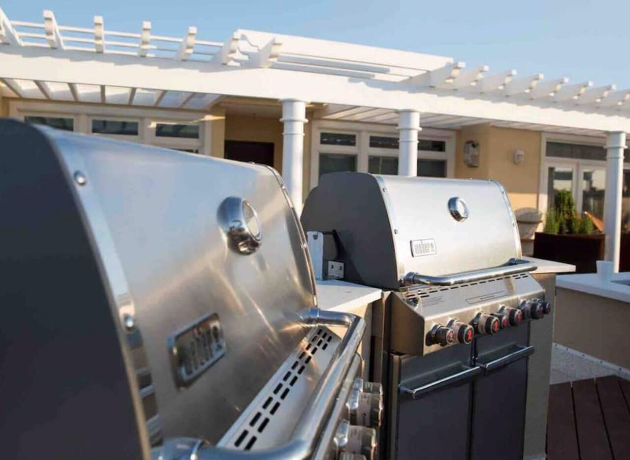 A patio with two stainless steel barbecue grills.