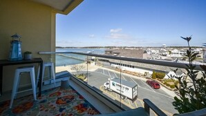 A balcony with a view of a parking lot and a body of water.