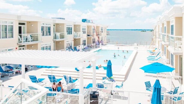 A cruise ship deck with a swimming pool, sun loungers, and a view of the sea.