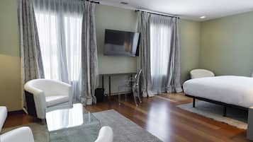 A modern hotel room with a bed, a TV, a desk, and two chairs.