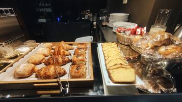 Un bufé con diversos pasteles, pan y una hogaza grande.