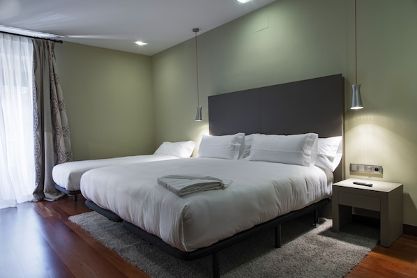 Un dormitorio moderno con una cama grande, mesitas de noche y un velador.