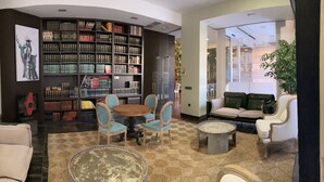 A cozy reading area with a bookshelf, a round table, and comfortable seating.