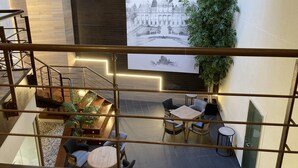 A modern interior with a staircase, seating area, and a large wall-mounted display.