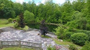 A stone pathway leading to a pond surrounded by lush greenery and trees.
