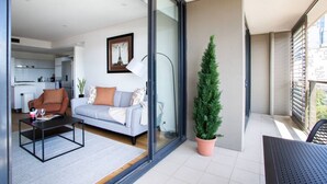 Un appartement moderne comprenant un salon, un coin repas et un balcon agrémenté d’un pot de fleurs.