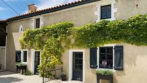 A building with a stone-paved entrance, a black metal gate, and potted plants near the entrance. - Gîte des Ruches, Peaceful & Homely 1 bedroom Gîte with pool (Chives)