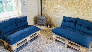 A rustic room with stone walls, a wooden ceiling, and two blue cushioned benches made from wooden pallets. - Gîte des Ruches, Peaceful & Homely 1 bedroom Gîte with pool (Chives)