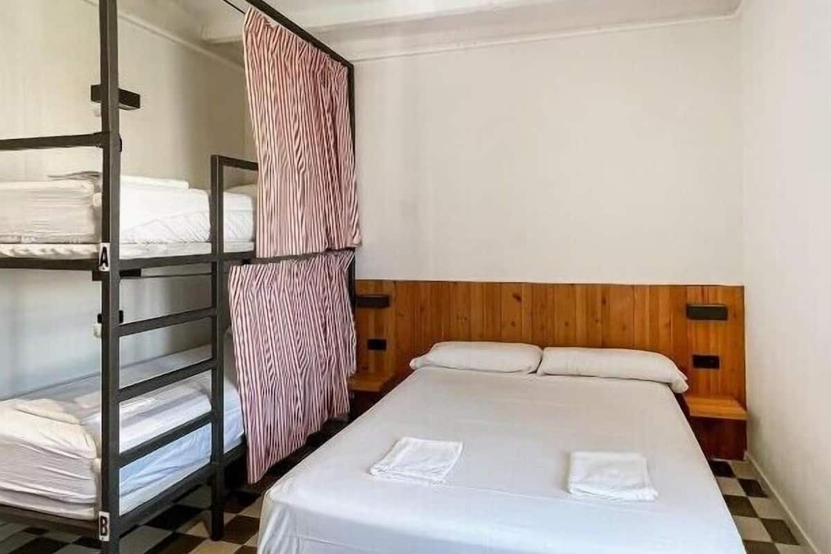 A room with a bunk bed, a single bed, a checkered floor, and a wooden headboard.