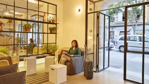 A hotel lobby with a seating area, a reception desk, and a view of the street through large glass doors. - The Boc Hostels Palma - Youth Hostel (Palma de Mallorca)