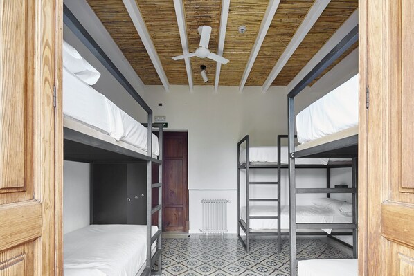 Un dormitorio con literas, un ventilador de techo, un radiador y un piso estampado.