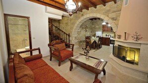 Amplia sala de estar con chimenea, muebles de madera y paredes de piedra.