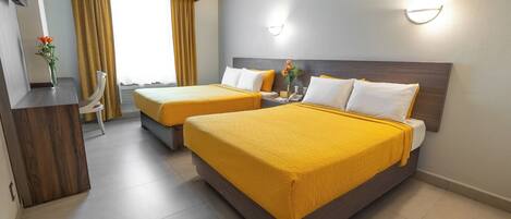 Habitación de hotel con dos camas, un escritorio y una silla.