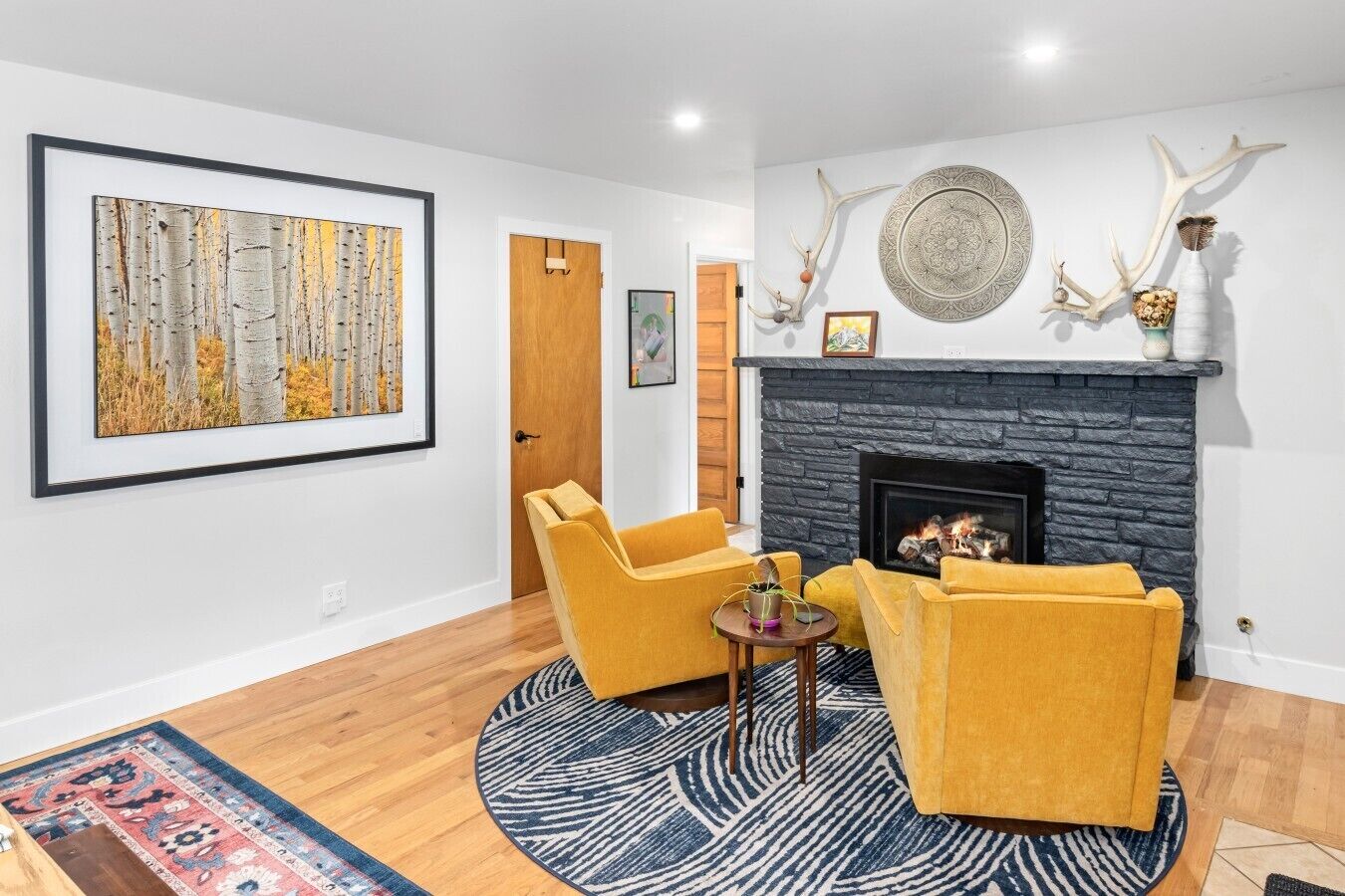 A living room with a fireplace, a framed painting, and antler decorations.