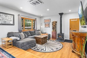 A cozy living room with a sectional sofa, a fireplace, and a television mounted on the wall.
