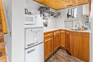 Una cocina compacta con un refrigerador blanco, gabinetes de madera, un microondas y un lavamanos.