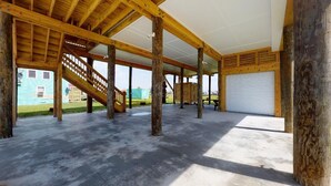 Un espace extérieur abrité, doté d’un sol en béton, de poutres en bois et d’un escalier.