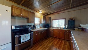 A kitchen with wooden cabinets, a stainless steel stove, a microwave, and a chalkboard menu. - The Mango Hut: 2  BR, 1  BA House in Port Bolivar, Sleeps 8 (Port Bolivar)