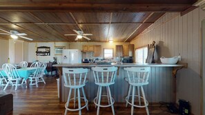 Una cocina con armarios de madera, una barra con taburetes y una zona de comedor con sillas.