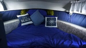 Una cama con un edredón azul y dos almohadas, una con un diseño de brújula y otra con texto.