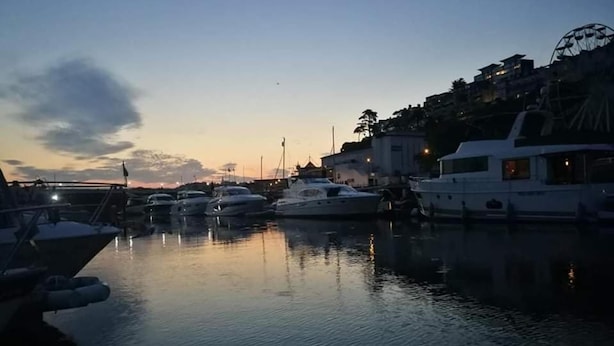 Un puerto deportivo al anochecer con varios yates amarrados.