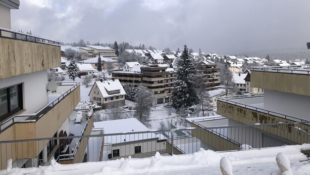 Un quartier résidentiel où les bâtiments sont recouverts de neige et où le ciel est dégagé.
