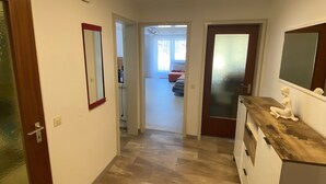 Un couloir avec un luminaire moderne, un miroir et une porte en bois.